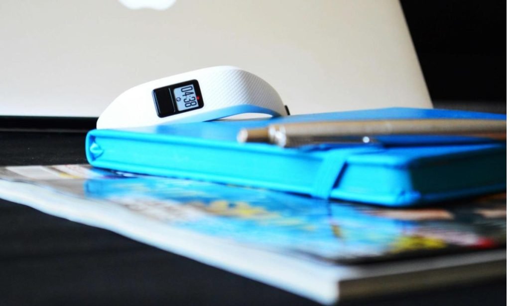 stack of books with a fitness tracker in focus on the background