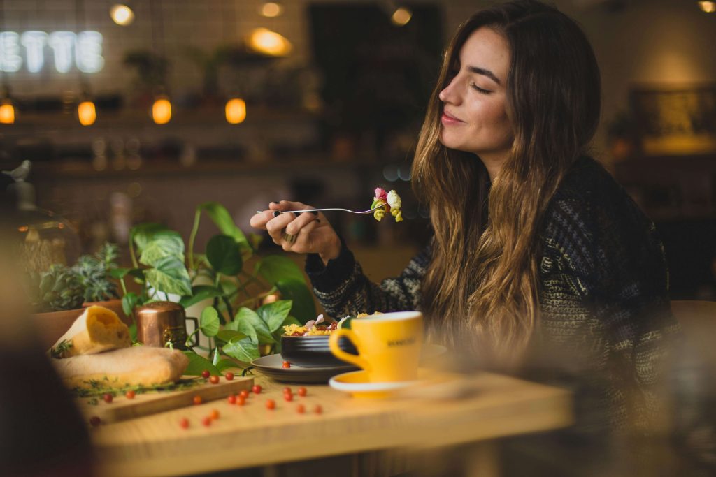 A woman savours a meal at a table with low, romantic lighting