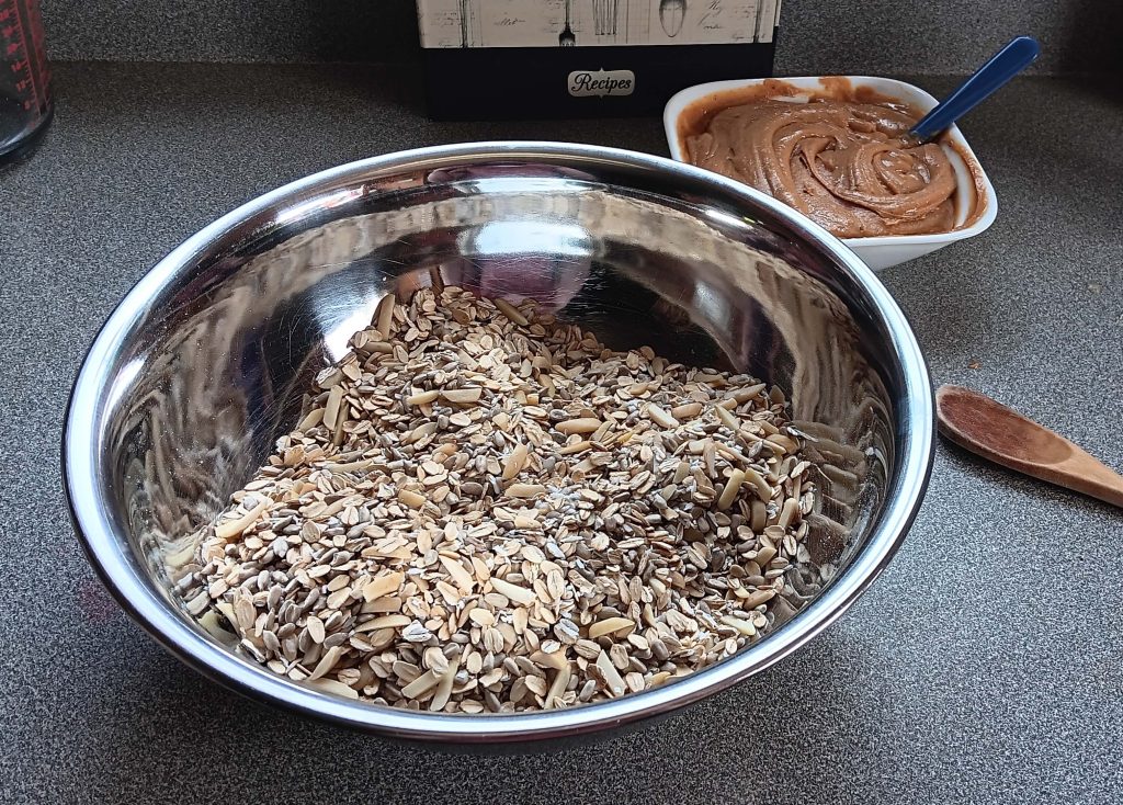 two bowls are shown - a large one with dry ingredients and a smaller one with the peanut butter and honey combined