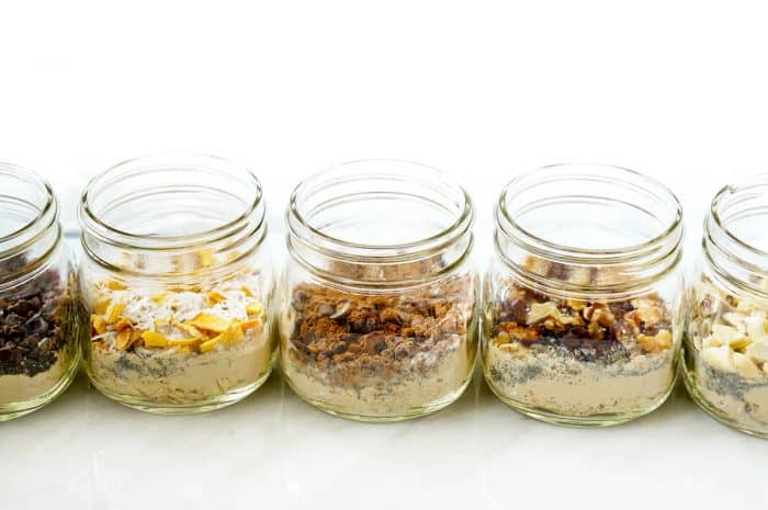 line up of mason jars filled with the ingredients for high protein over night oats
