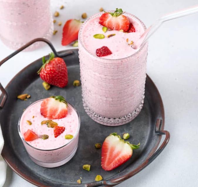 strawberry cottage cheese smoothie in a glass with chunks of strawberry on top.